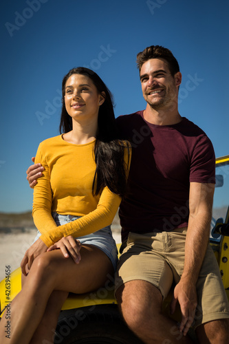 Happy caucasian couple woman sitting in beach buggy by the sea both looking ahead