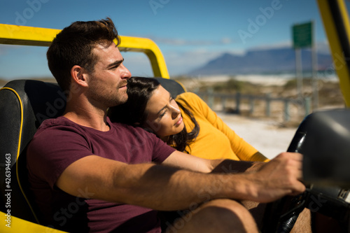 Happy caucasian couple sitting in beach buggy by the sea relaxing