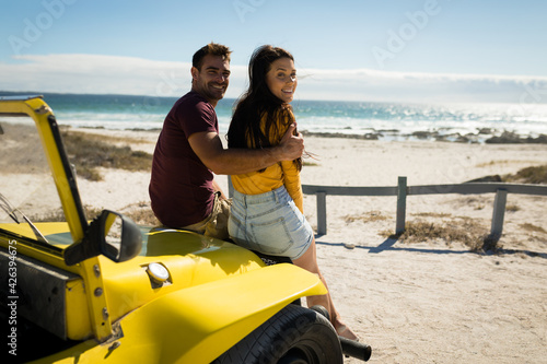 Happy caucasian couple sitting in beach buggy looking to camera