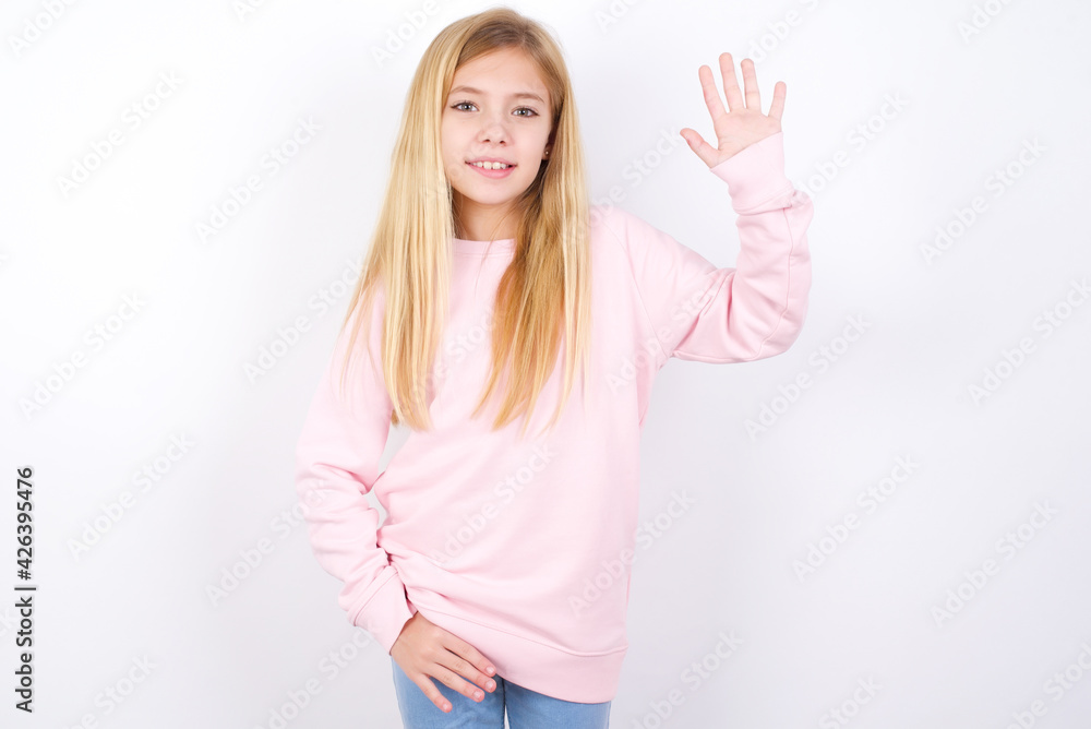 beautiful caucasian little girl wearing pink hoodie over white background waiving saying hello or goodbye happy and smiling, friendly welcome gesture. beautiful caucasian little girl wearing pink hoodie over white background waiving saying hello or goodbye happy and smiling, friendly welcome gesture.