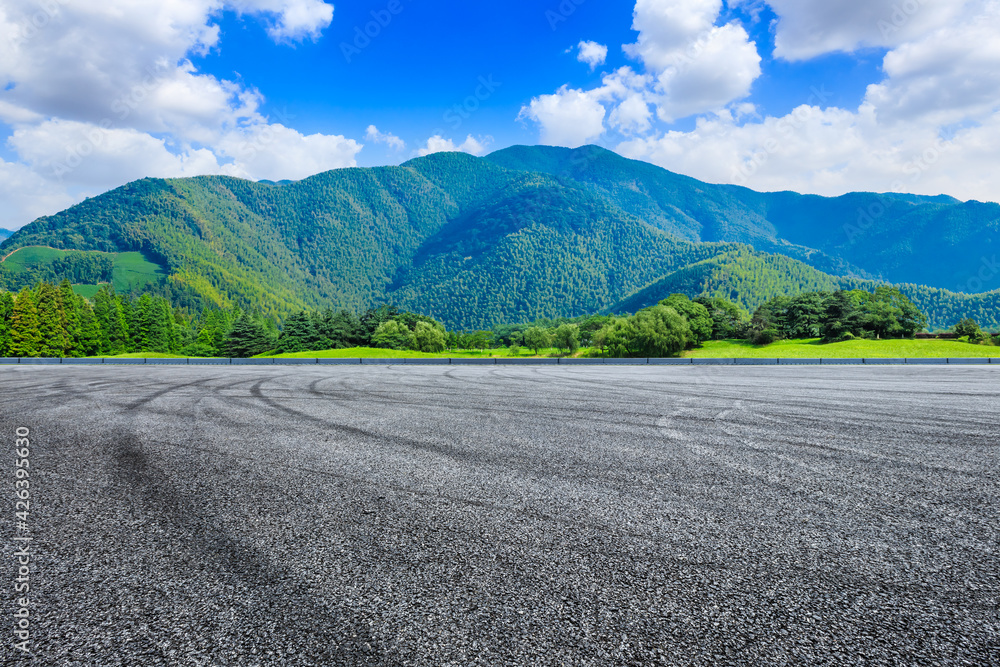 Empty asphalt road and green mountain under blue sky.