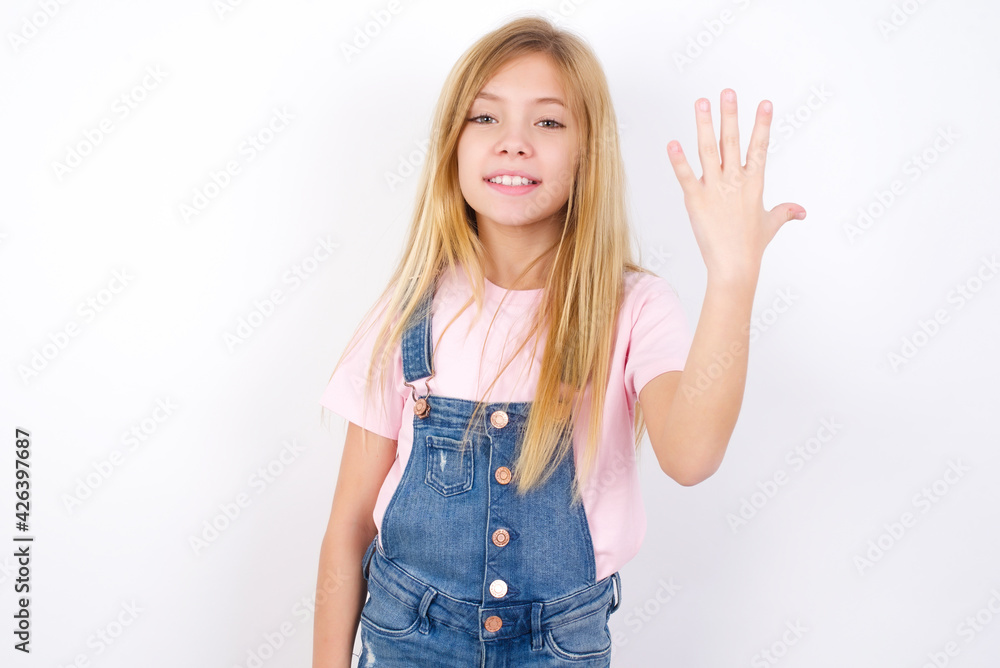 beautiful Caucasian little girl wearing denim overalls over white background smiling and looking friendly, showing number five or fifth with hand forward, counting down beautiful Caucasian little girl wearing denim overalls over white background smiling and looking friendly, showing number five or fifth with hand forward, counting down