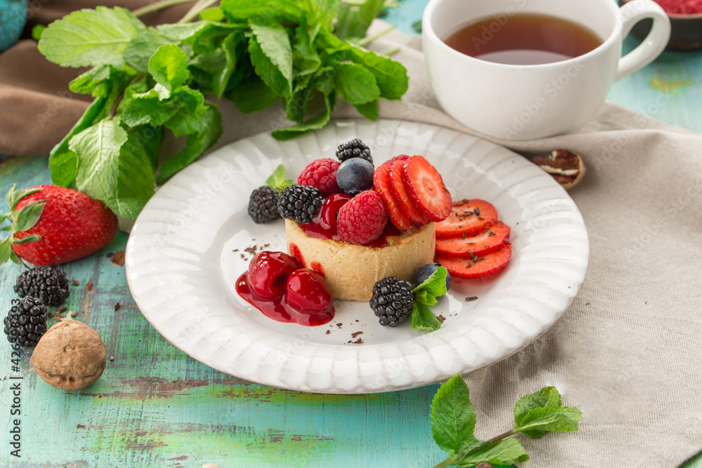 Sweet tart with fresh raspberry strawberry blackberry and cup of tea on the table Sweet tart with fresh raspberry strawberry blackberry and cup of tea on the table