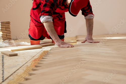 фотографія Handyman installing wooden flooring, Worker laying parquet flooring