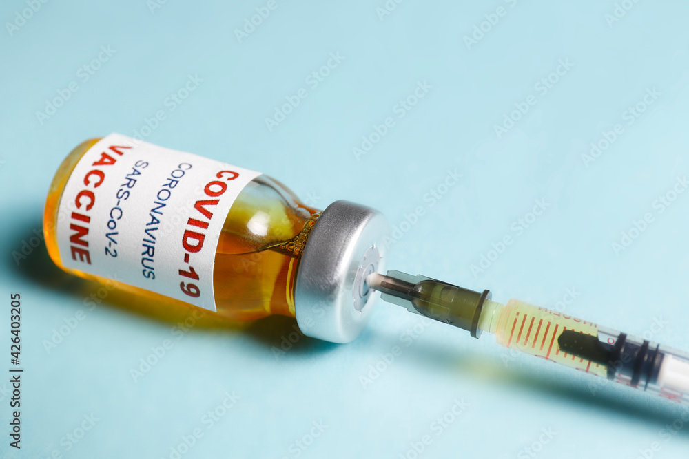 Macro shot of antiviral vaccine vial with syringe for immunization against covid-19 virus. Isolated on blue background with copy space for text. Close up, top view Macro shot of antiviral vaccine vial with syringe for immunization against covid-19 virus. Isolated on blue background with copy space for text. Close up, top view