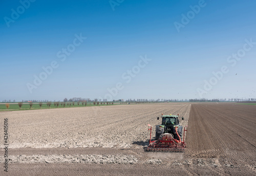 farmer works his land on rural countryside of noord beveland in dutch province zeeland on sunny spring day photo