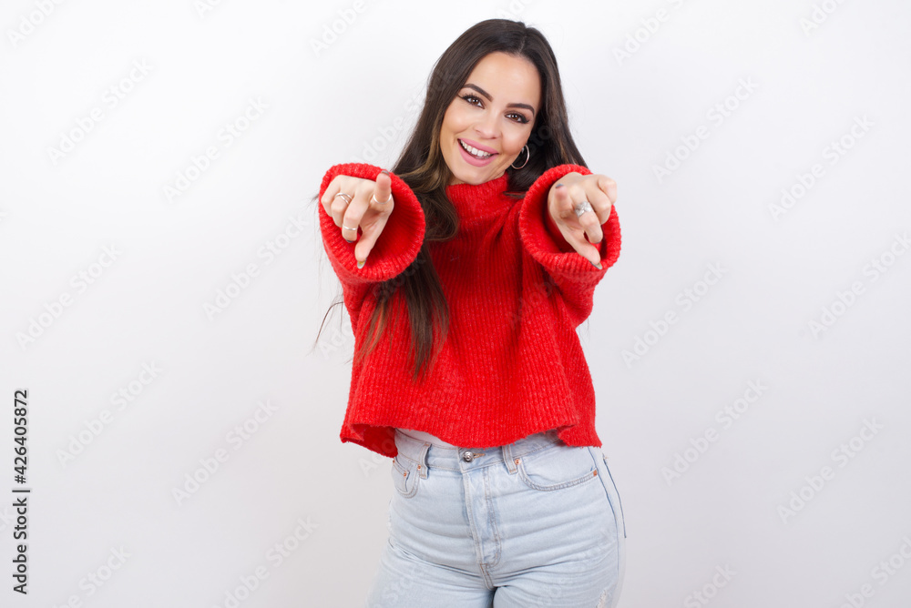 Close-up portrait of surprised young beautiful brunette woman wearing red knitted sweater over white wall pointing with two fingers to the camera saying: I choose you!, looking up with open mouth. Close-up portrait of surprised young beautiful brunette woman wearing red knitted sweater over white wall pointing with two fingers to the camera saying: I choose you!, looking up with open mouth.