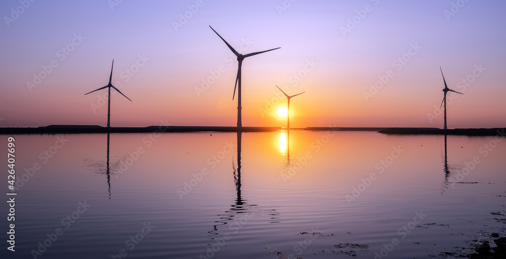 wind turbines and colorful sunrise reflected in water