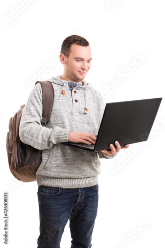 Young guy in casual clothing and backpack holding open laptop