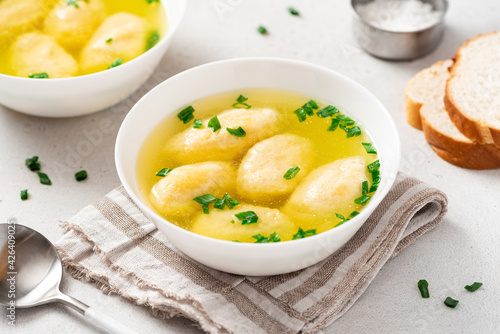 Griessnockerlsuppe. Soup with semolina dumplings in a white bowl on a light concrete background. Bavarian cuisine. photo