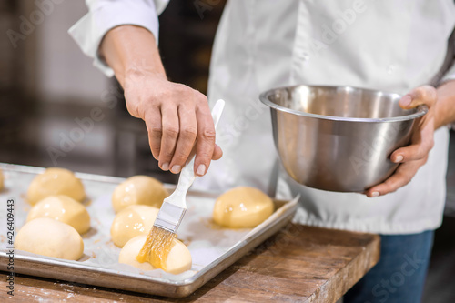 Mans hands skillfully covering rolls with glaze