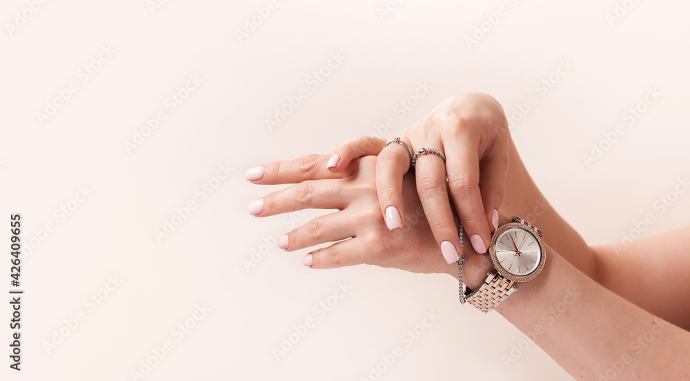 Female hands with trendy light pink manicure wear stylish jewerly. Female hands with trendy light pink manicure wear stylish jewerly.