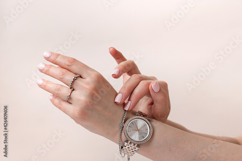 Female hands with trendy light pink manicure wear stylish jewerly.