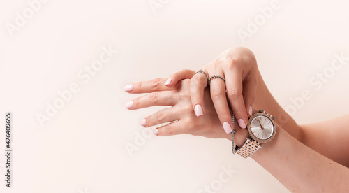 Female hands with trendy light pink manicure wear stylish jewerly.