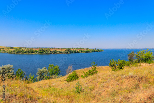 Summer landscape with beautiful river, green trees and blue sky © olyasolodenko