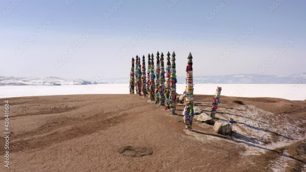 Serge pillars on Cape Burkhan in winter, snow-covered Olkhon island, frozen and ice-covered Lake Baikal. The tourist carefully examines the sacred sights. Serge pillars on Cape Burkhan in winter, snow-covered Olkhon island, frozen and ice-covered Lake Baikal. The tourist carefully examines the sacred sights.