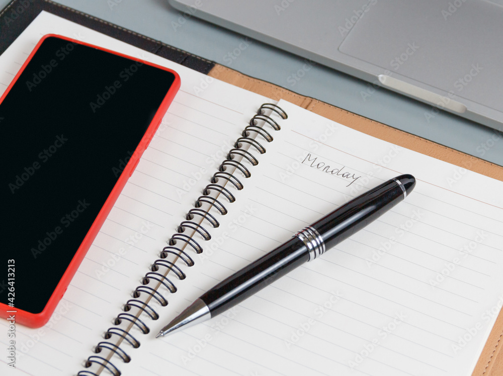 Opened agenda with handwritten MONDAY on a grey close up Opened agenda with handwritten MONDAY on a grey close up