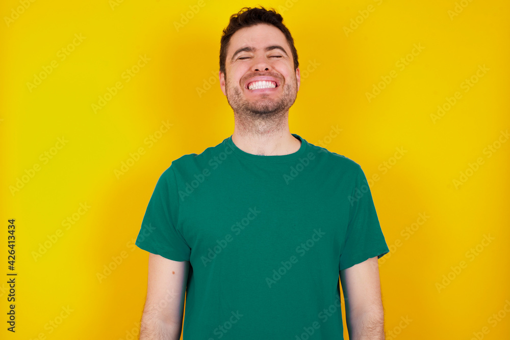 young Caucasian man wearing green T-shirt against yellow wall very happy and excited about new plans. young Caucasian man wearing green T-shirt against yellow wall very happy and excited about new plans.