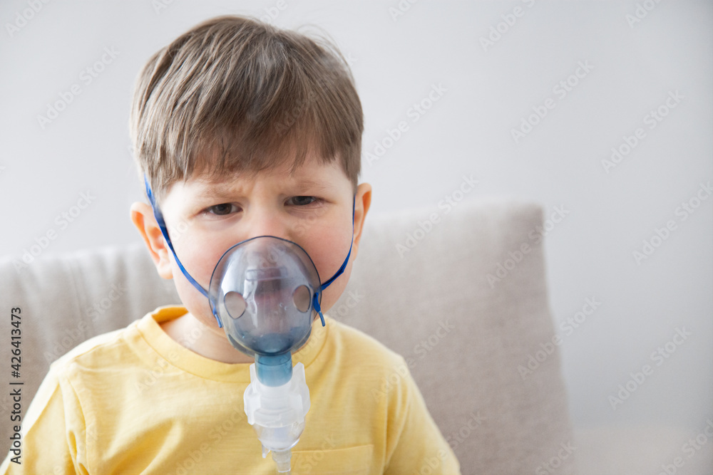 Crying little Boy in a mask from a nebulizer makes inhalation 