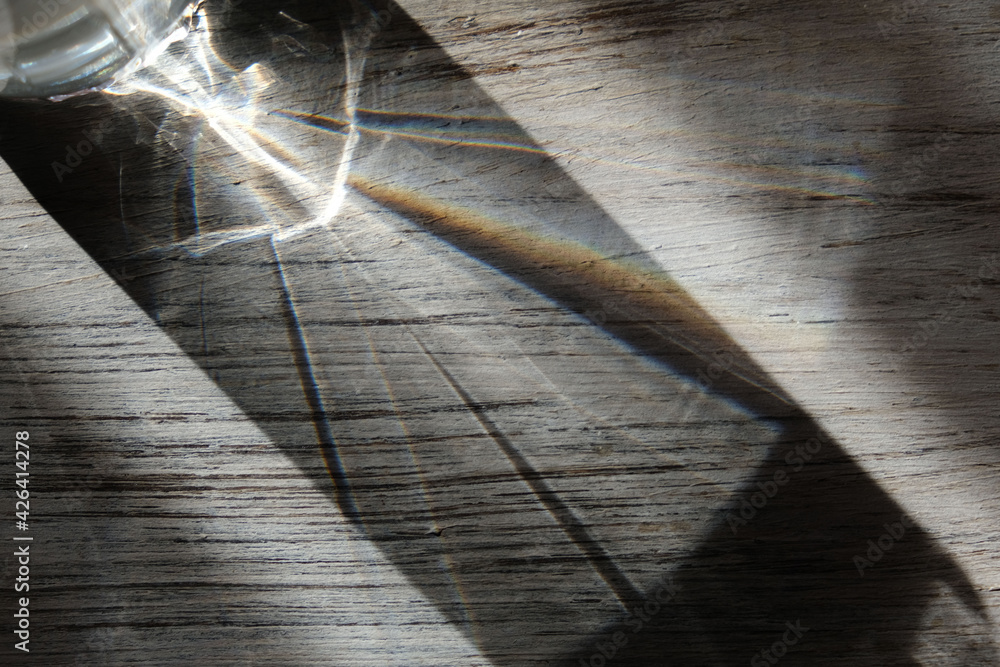 Obraz premium Wooden grey abstract background with light and shadows caustic effect. Light passes through a glass. Blurred light refraction texture overlay. effect like a space theme