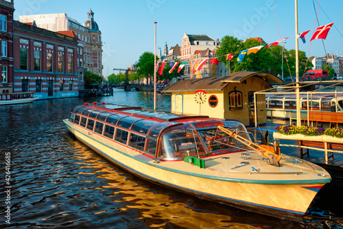 Tourist boats moored in Amsterdam canal pier on sunset photo