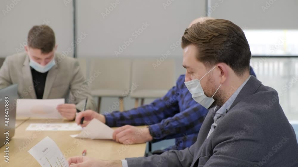 Business people having a meeting, working in the office, wearing medical mask.