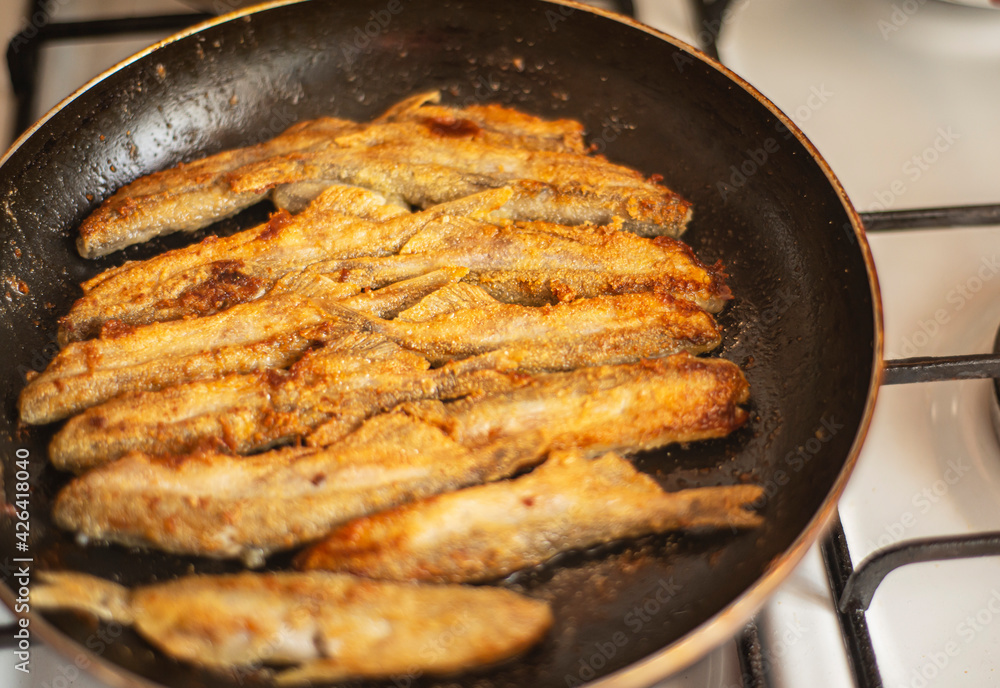 capelin in a pan fried in corn flour, Mallotus villosus - sea ray-finned fish of the smelt family, simple homemade food fried fish, simple homemade food concept, home cooking