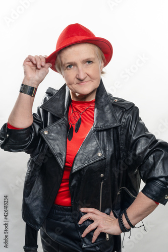 Elegant woman at the age, in a red hat and a red sweater.older model posing in studio. Youth in older age concept