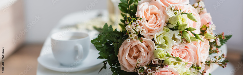 selective focus of wedding bouquet near coffee cup on blurred background, banner. - obrazy, fototapety, plakaty 