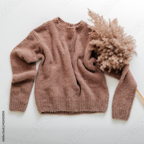 Warm stylish homewear winter spring outfit brown warm knitted sweater with cortaderia branch flower pampas grass. Cashmere sweater fly on white. Knitted soft beige sweater with reed branch. square