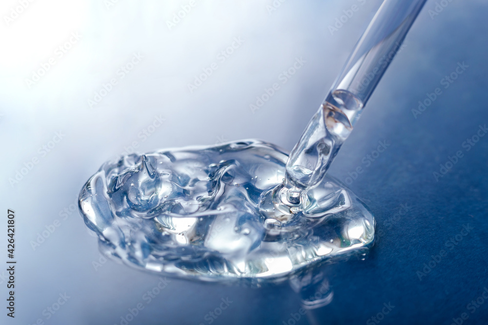Liquid transparent gel serum swatch with pipette on blue color glass background. Cosmetic product for skin care or medical clear liquid gel. Liquid transparent gel serum swatch with pipette on blue color glass background. Cosmetic product for skin care or medical clear liquid gel.