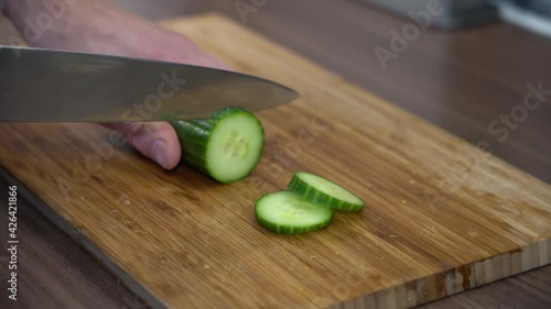 closeup of knife slicing cucumber on citchen counter photo