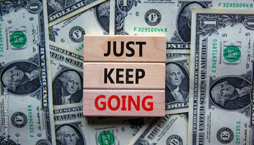 Just keep going symbol. Wooden blocks with words 'Just keep going'. Beautiful background from dollar bills. Business, just keep going concept, copy space.