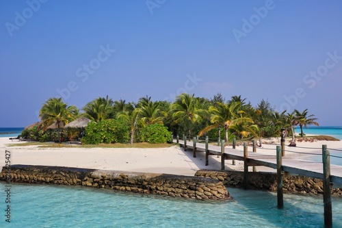 Paradisal Sandy Shore of Maldivian Resort with Palm Tree and Wooden Walkway. Maldives Island with Sandy Beach and Blue Sky.