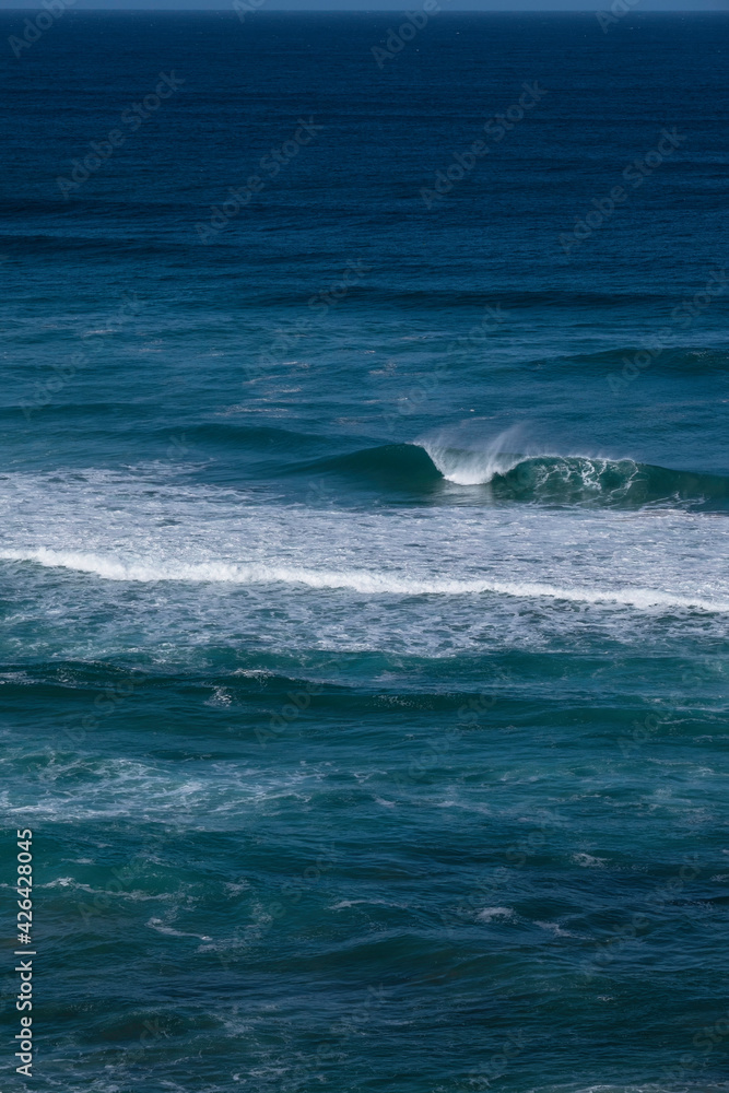 Fototapeta premium Big blue wave breaks in a dark blue ocean