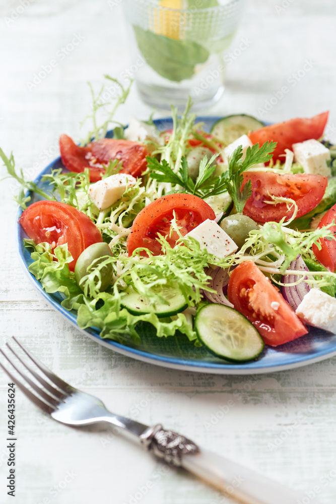 Salad with Green Olives, Tomatoes and Feta Cheese. Bright wooden background. Close up.	