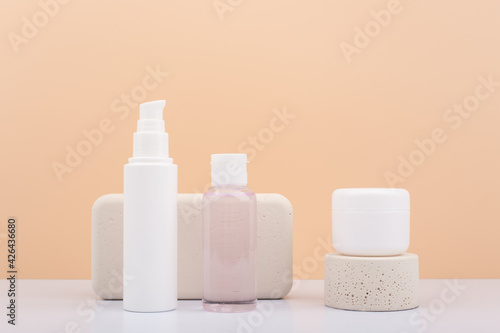 Set of natural organic beauty products for daily skin care with beige podiums against beige background. Face cream, lotion and balm, scrub or mask in white unbranded jars. 