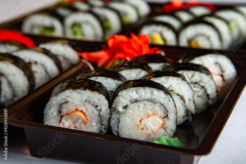 Japanese food rolls in plastic box. Sushi set in a plastic package close up isolated on a white background. Sushi for take away or sushi delivery.