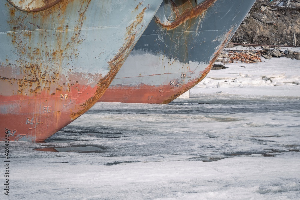 The bow of sea vessels close-up at the pier on the frozen river. Winter season The bow of sea vessels close-up at the pier on the frozen river. Winter season