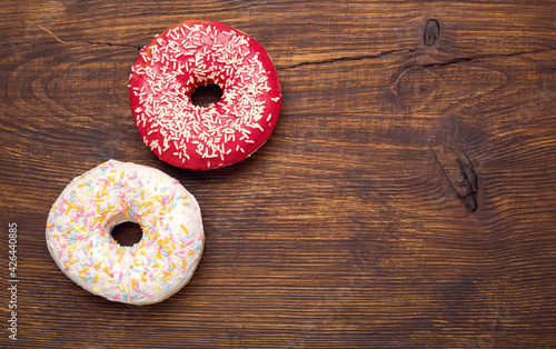Two donuts on a wooden plank background.