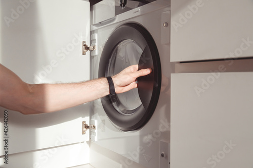 Billede på lærred man's hand opening built-in washing machine in kitchen