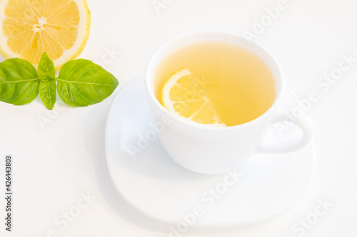 Cup of green tea with lemon slice, basil and mint isolated on white background