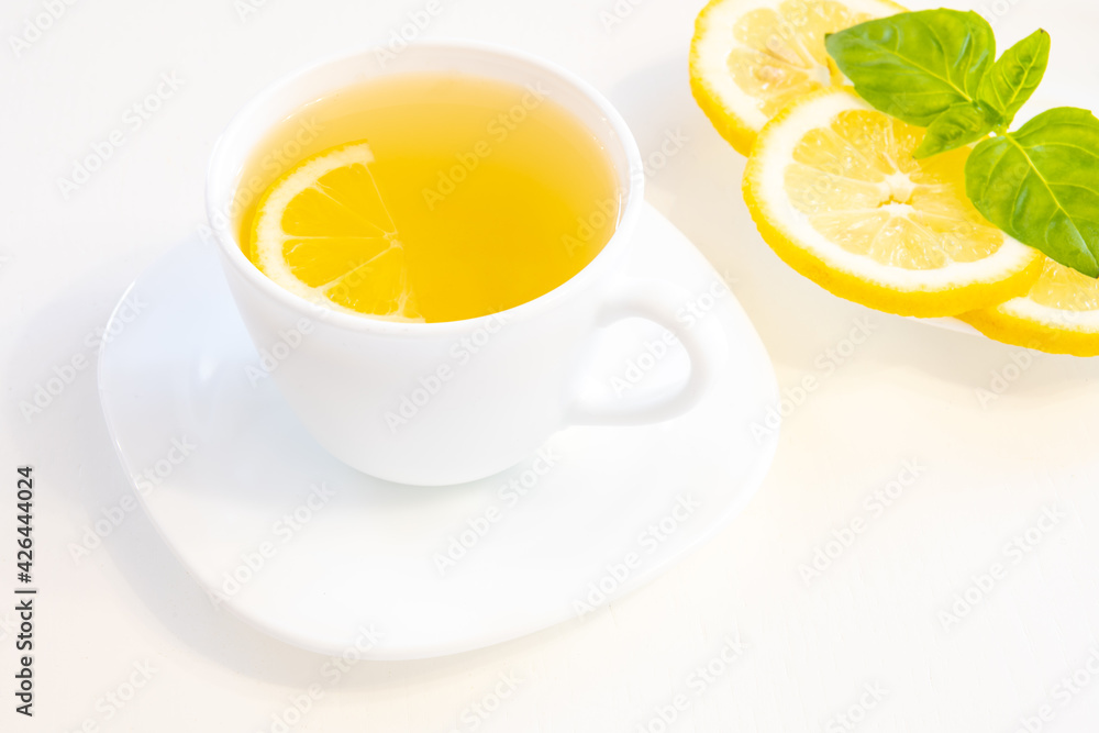Cup of tea with lemon slice, basil and mint isolated on white background