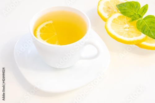 Cup of tea with lemon slice, basil and mint isolated on white background