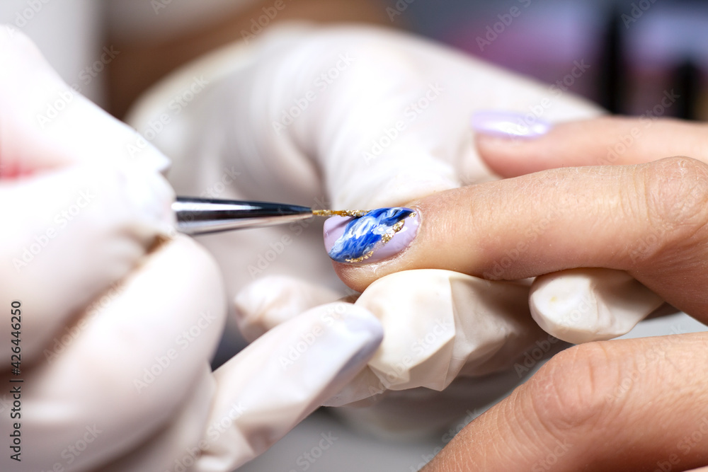 Nail design. The process of coating the nails with gel polish and drawing the design with a brush by a specialist in a beauty salon. Close-up. Space for text Nail design. The process of coating the nails with gel polish and drawing the design with a brush by a specialist in a beauty salon. Close-up. Space for text