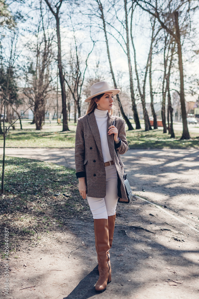 Full body portrait of beautiful woman wearing stylish blazer, hat and boots  in spring park. Female fashion Stock-Foto | Adobe Stock