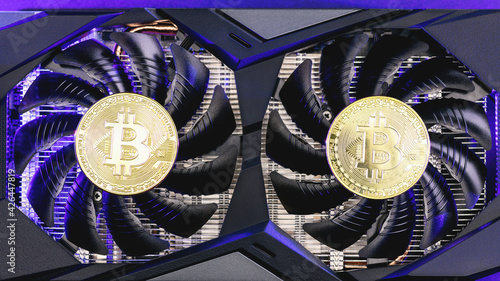 Two gold bitcoin on a video Card with blue backlight. Crypto currency, top view. Bitcoin mining concept