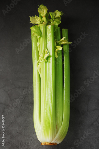 Fresh celery stalks on a black textured background.