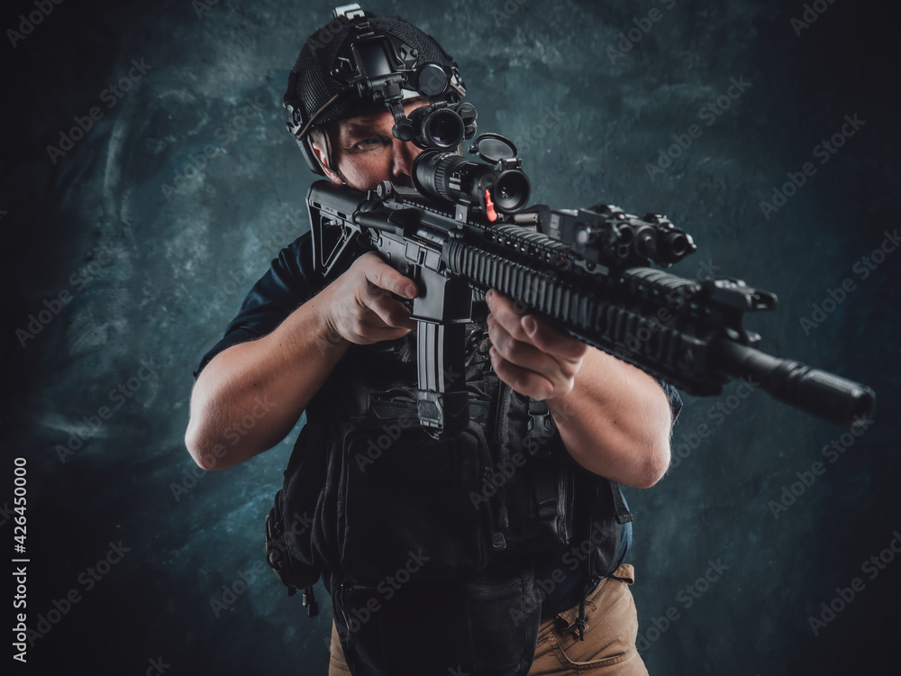 Dangerous and armed soldier aims a machine rifle in dark background