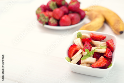 Banana strawberry salad cut into slices with mint leaves. Vitamin breakfast.